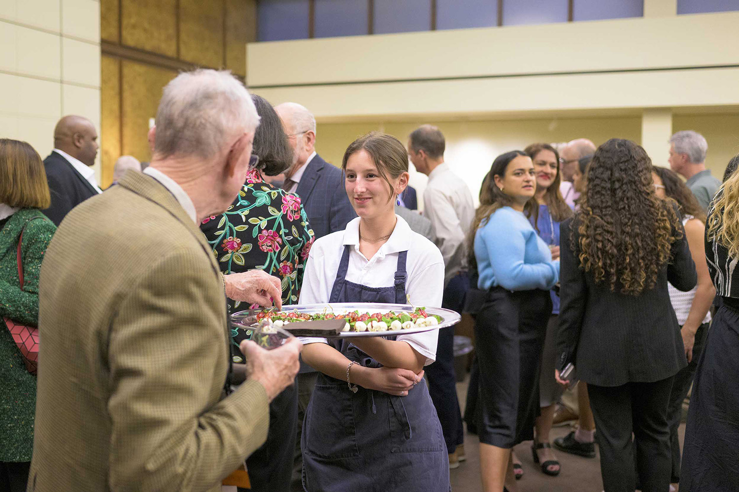 A student worker at the Athenaum serving hors d'oeuvres to a guest.