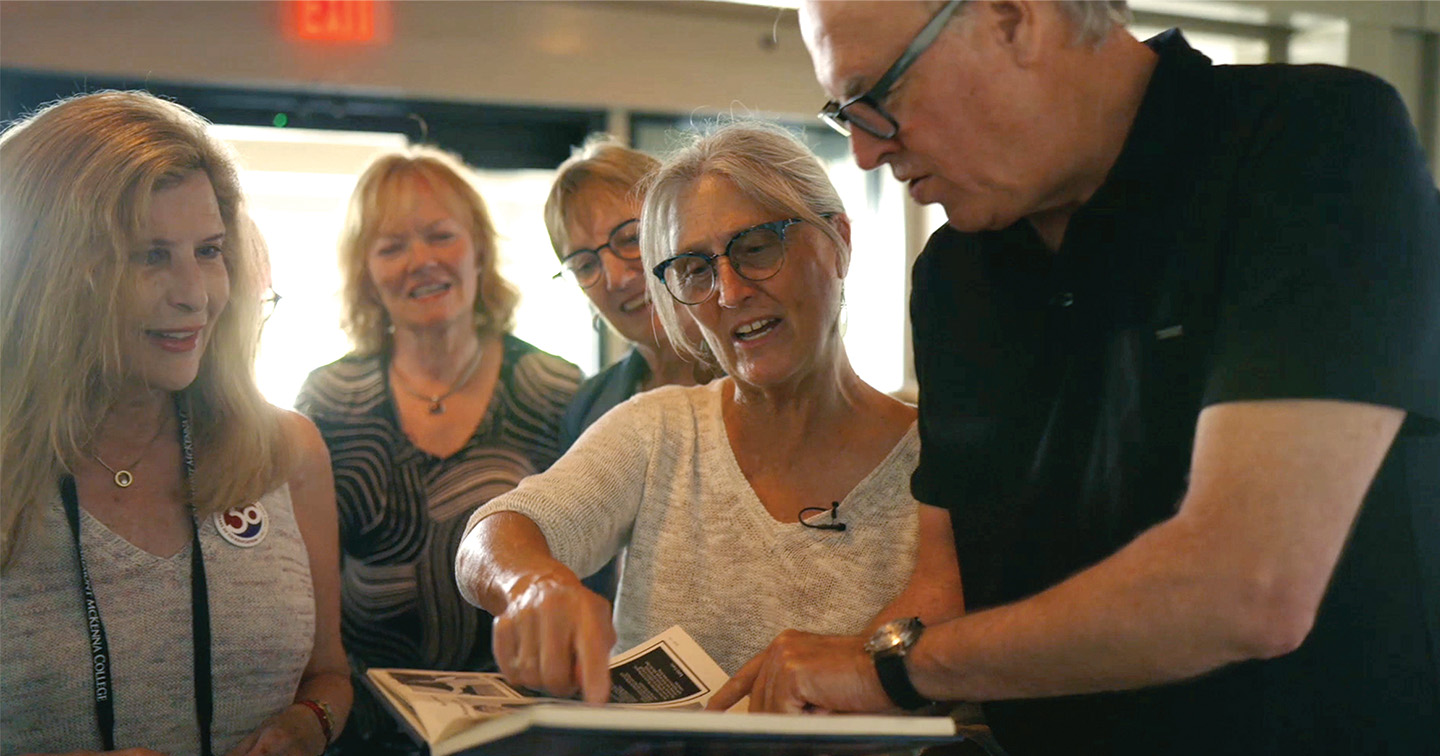 Members of the class of 1980 group looking through old yearbooks.