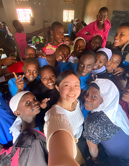 A CMC's student takes a selfie with young African students during internship trip.