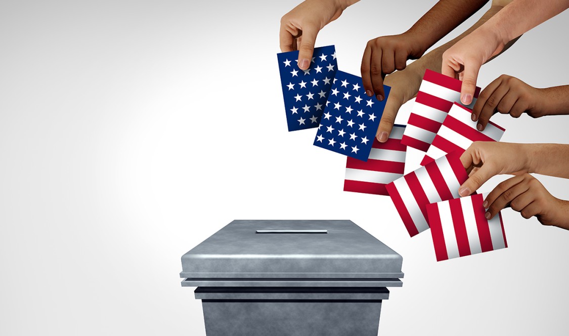Stock photo on plain white/light gray background of multiple hands coming from the top right corner holding cards arranged to look like a loose collage of the United States flag, all reaching for a gray ballot box in the middle.
