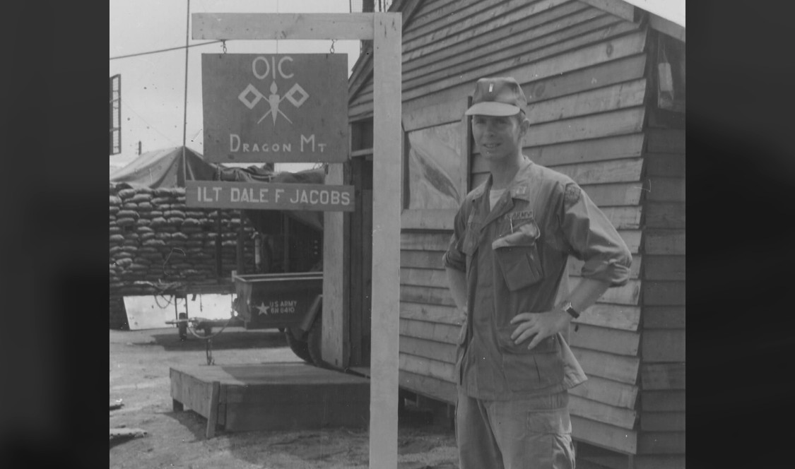 Black and white photo of Dale Jacobs '66 in fatigues outside his camp.