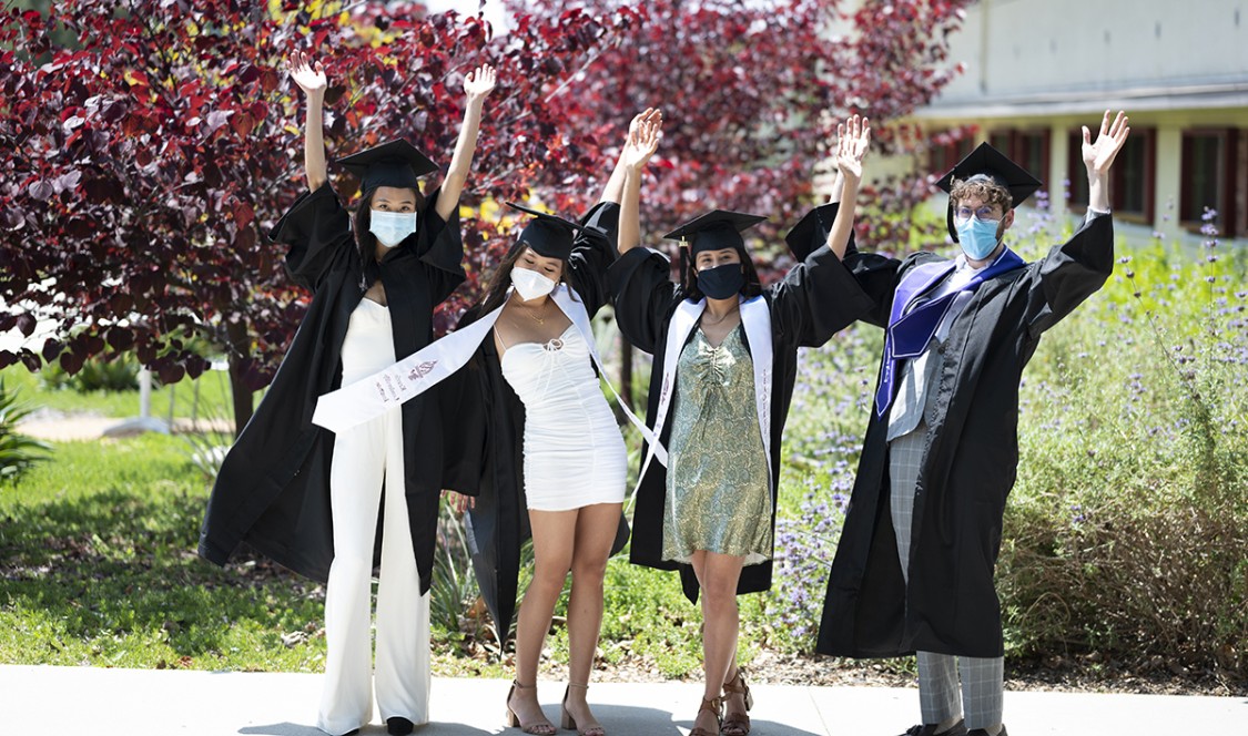Cheering CMC grads on campus wearing caps and gowns and masks