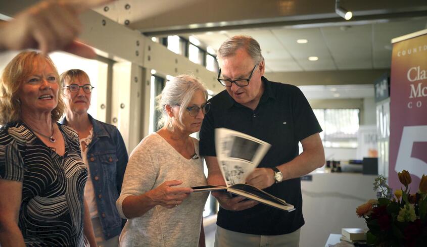 Class of 1980 classmates looking at yearbook