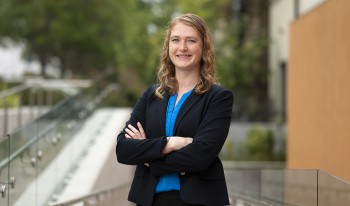 Professor Sarah Cannon poses with a smile and crossed arms on campus