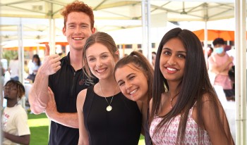 Four students smile together for the camera at the SIF booth during the Club and Institute Fair