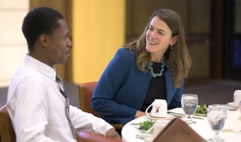 Jennifer Burns speaks with a student at the head table during Ath's dinner service.