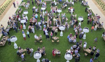 Down shot view from Kravis Center of Gann Quadrangle during Alumni Weekend 2022's wine tasting event shows alumni scattered around full glasses in hand.