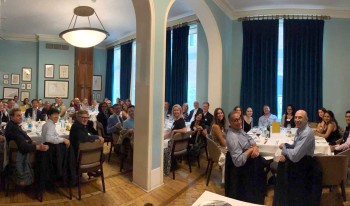 CMC alumni, parents, and students photographed together before sharing a white table cloth meal in London.