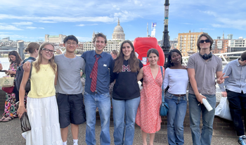Group of students hugging posing in front of Shakespeare Globe. 