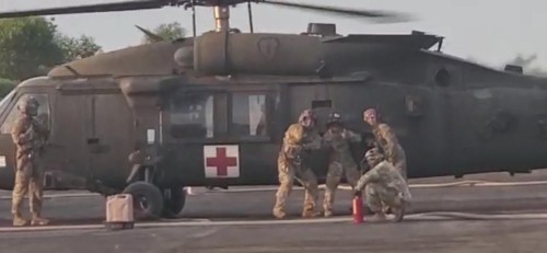 Lindsay with unit in front of a helicopter.