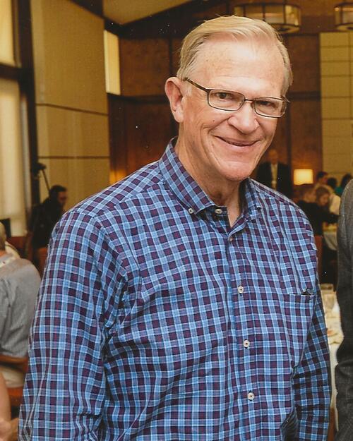 Man with blond short hair wearing glasses and blue with red flannel.