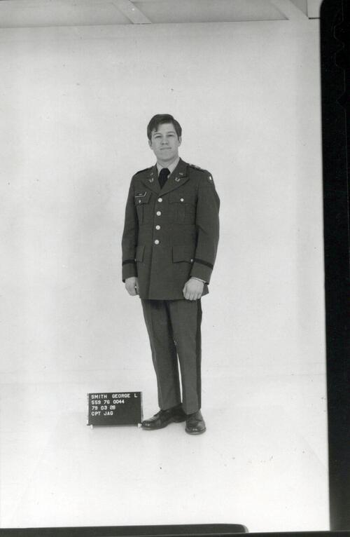 Man in military uniform in front of white backdrop inside photo studio. 