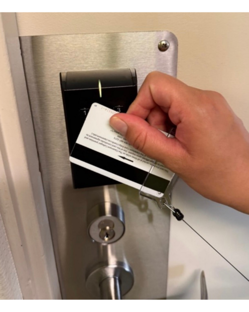Hand holding white card over black door scanner.