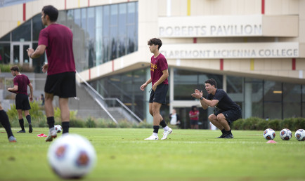 A low angle photo of CMS Men's Soccer practicing on the field in front of Roberts Pavilion