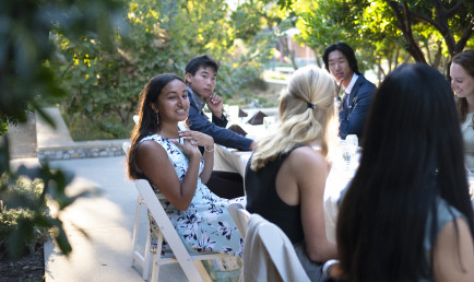 Students in cocktail dresses and suits enjoy open dialogue at the Ath head table, held outdoors during the COVID-19 pandemic.