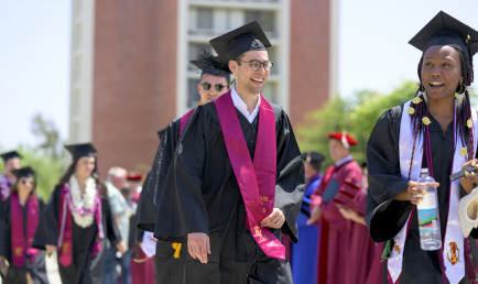 Smiling graduates of the classes of 2020 and 2021 file into the commencement tent on Parents Field as faculty welcome them.