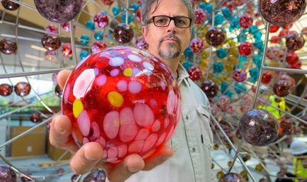 Damián Ortega holding glass orb.