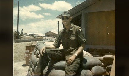 Russ as a young man in the service, seated on stacked bags of sand.