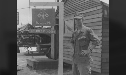 Black and white photo of Dale Jacobs '66 in fatigues outside his camp.