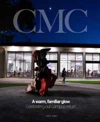 CMC Magazine photo cover for Fall 2021: Collins Dining Hall lit up at night behind one of the new Carol Bove sculptures. A student walks along the path between the glass windows with 75th Anniversary decals applied, and the sculpture. Below the sculpture is the text &quot;A warm, familiar glow: Celebrating our campus return.&quot;