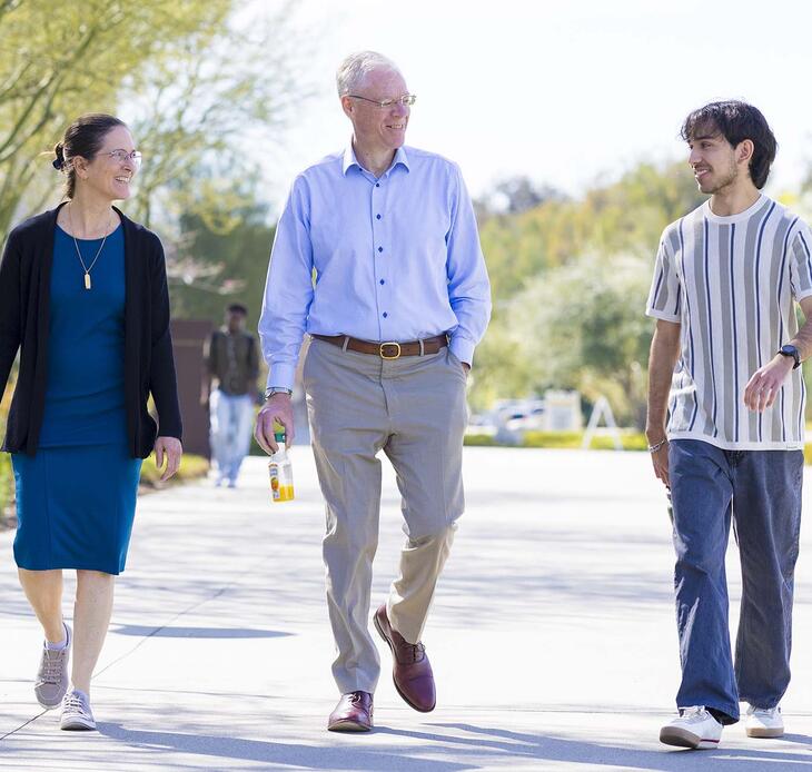 President Will Dudley and wife Dr. Carola Tanna walking with student on campus